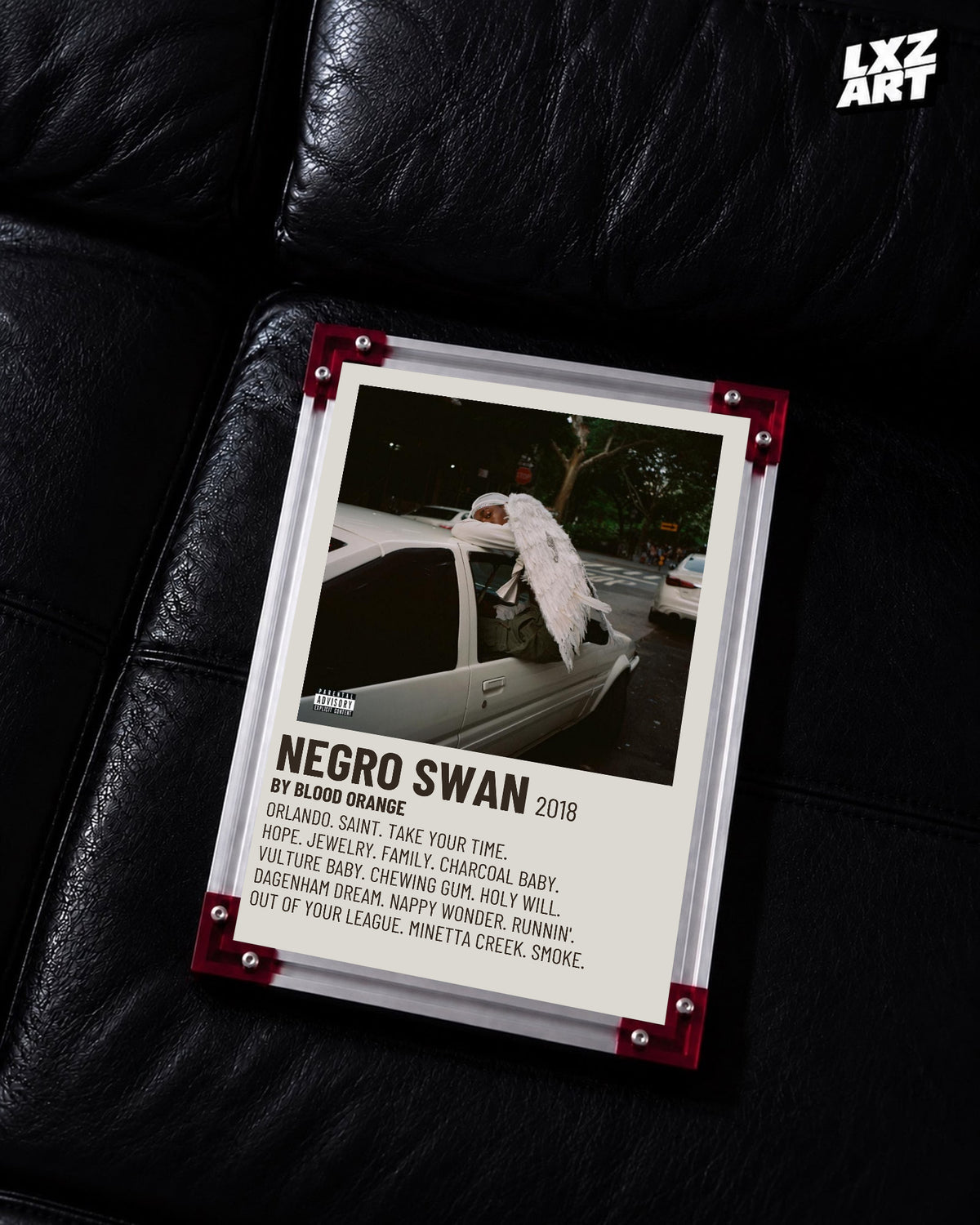 Blood Orange Negro Swan cream tracklist poster displayed on a black leather sofa in the red-corner frame; unframed print, frame not included