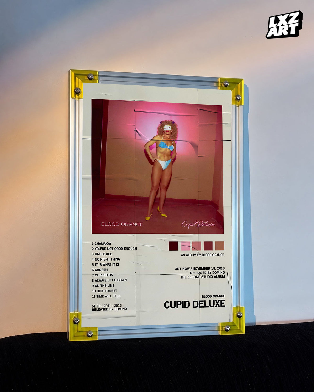 Blood Orange Cupid Deluxe distressed tracklist poster displayed against a warm-lit wall in the yellow-corner frame; unframed print, frame not included