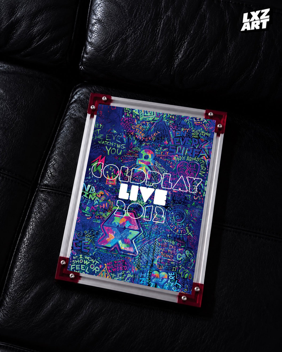 Coldplay Live 2012 Graffiti Concert Film Poster displayed on a black leather sofa in a red-corner frame; unframed print, frame not included