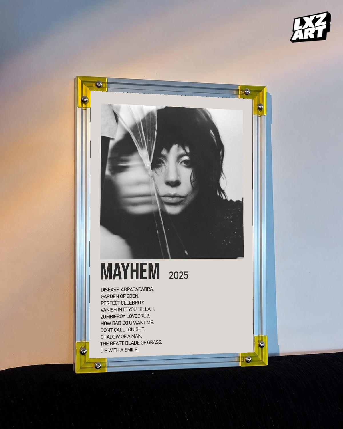 Lady Gaga Mayhem tracklist poster displayed against a warm wall in a yellow corner frame; unframed print, frame not included