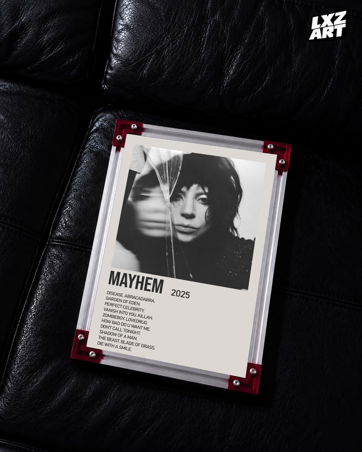 Lady Gaga Mayhem tracklist poster displayed on a black leather sofa in a red corner frame; unframed print, frame not included