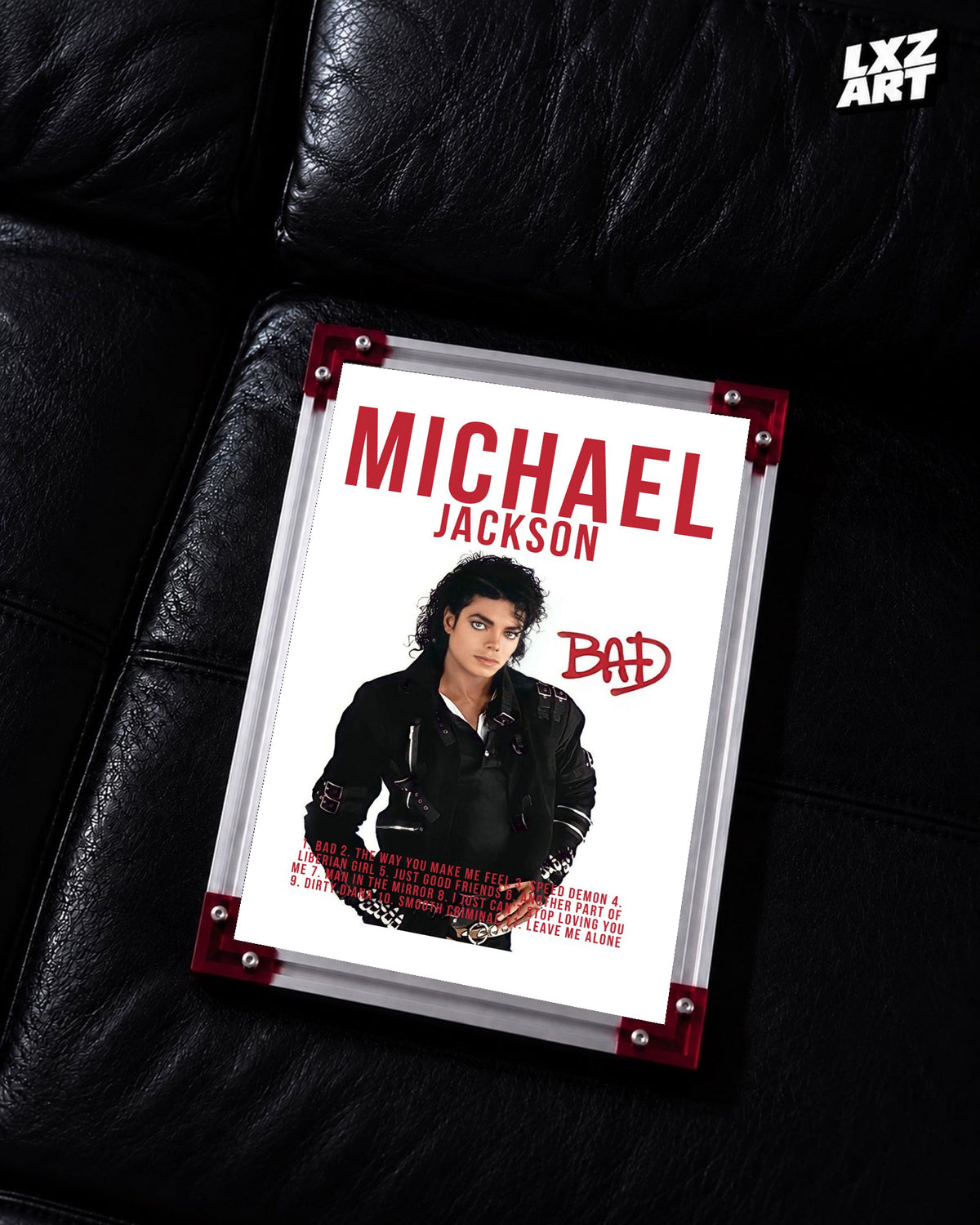 Michael Jackson Bad Red Typography tracklist poster displayed on a black leather sofa in a red corner frame; unframed print, frame not included