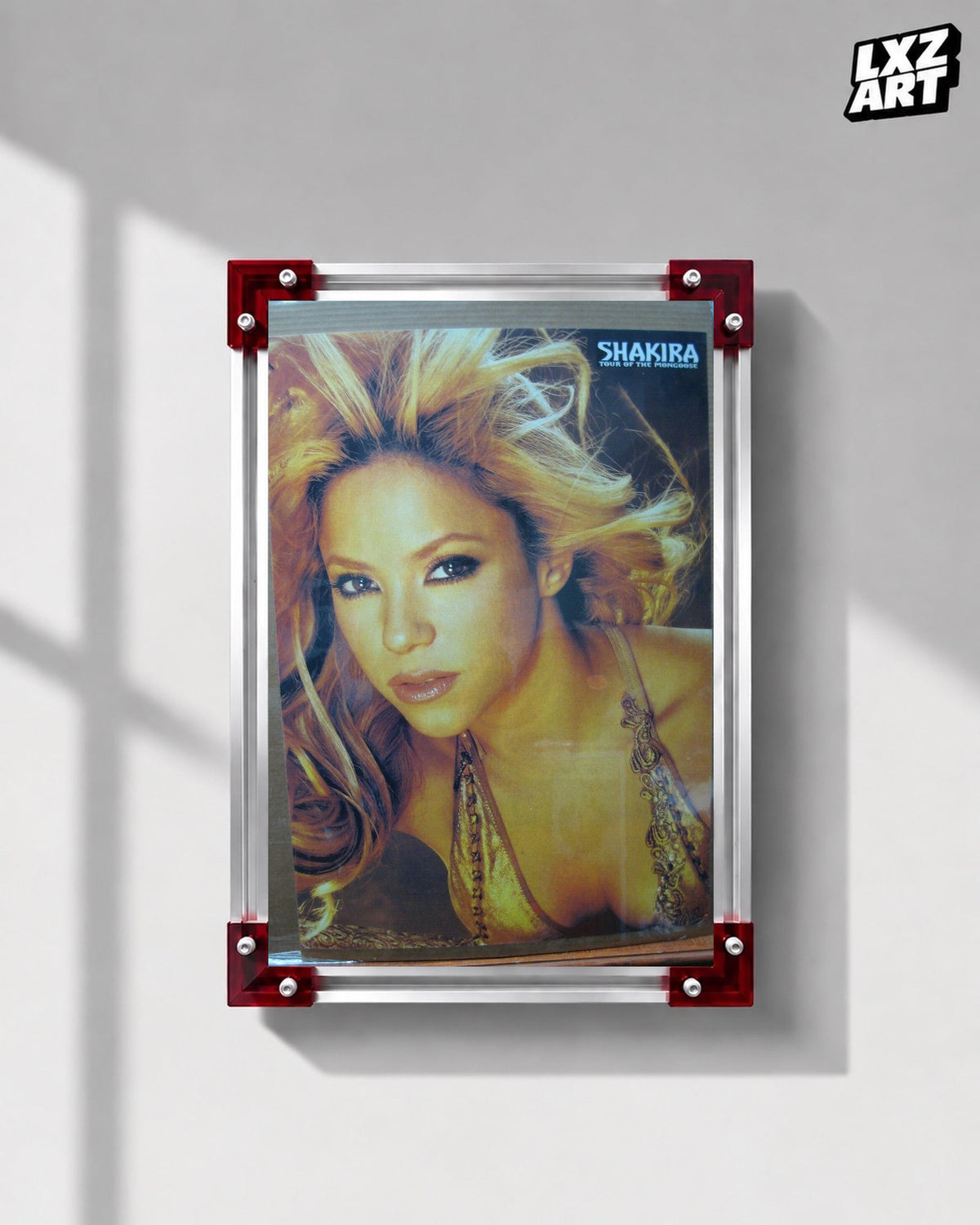 Shakira Tour of the Mongoose concert tour poster displayed on a gray wall in a red corner frame; unframed print, frame not included