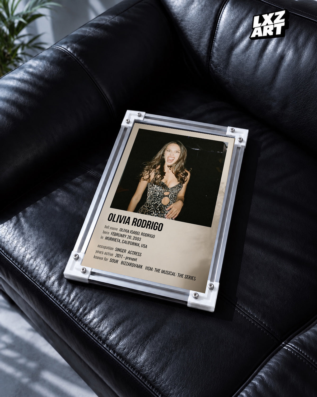 Olivia Rodrigo Biography Portrait Poster — black leather sofa; frame for display only