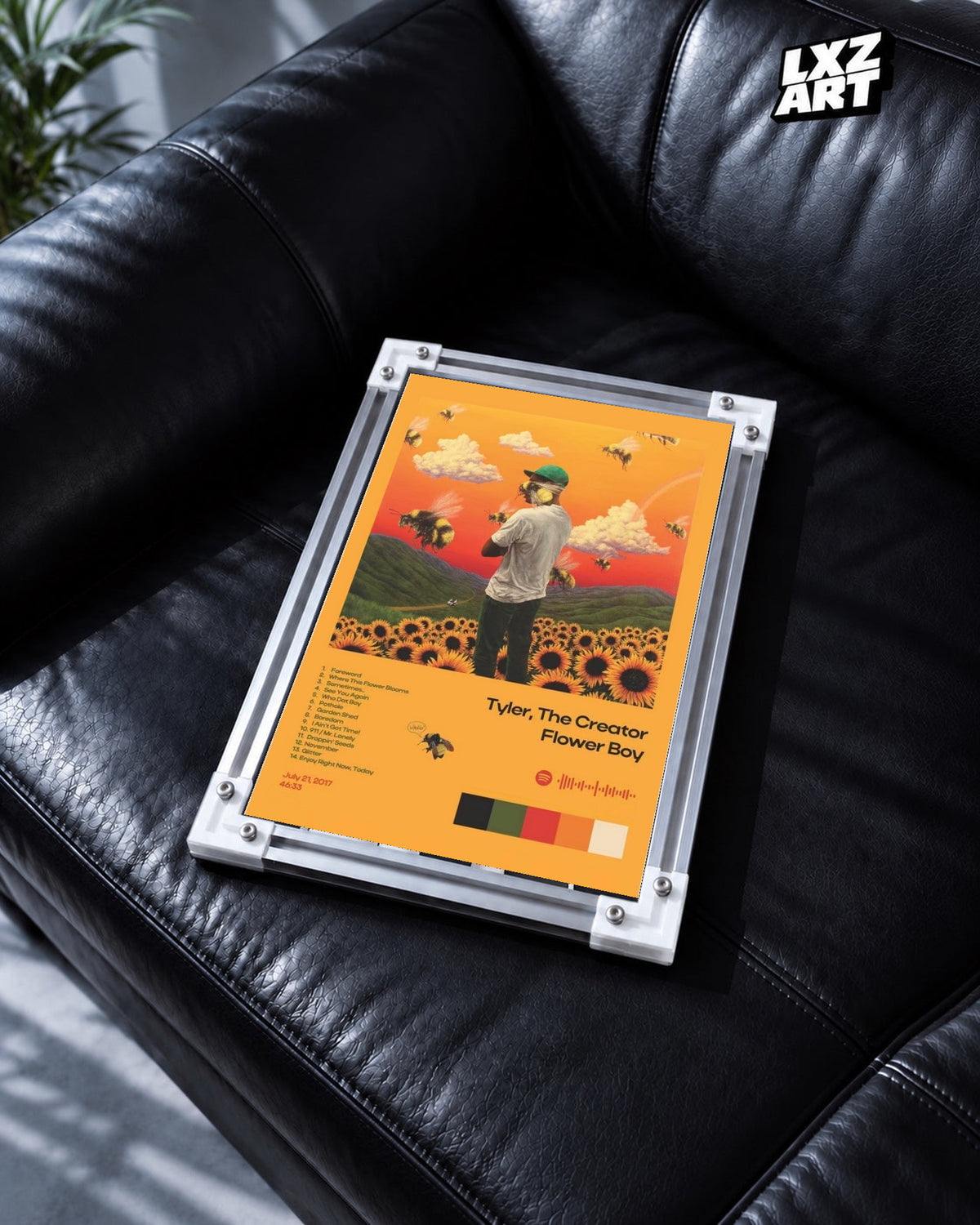 Tyler, The Creator Flower Boy Tracklist Poster in white-corner frame on black leather sofa. Frame shown for display only.