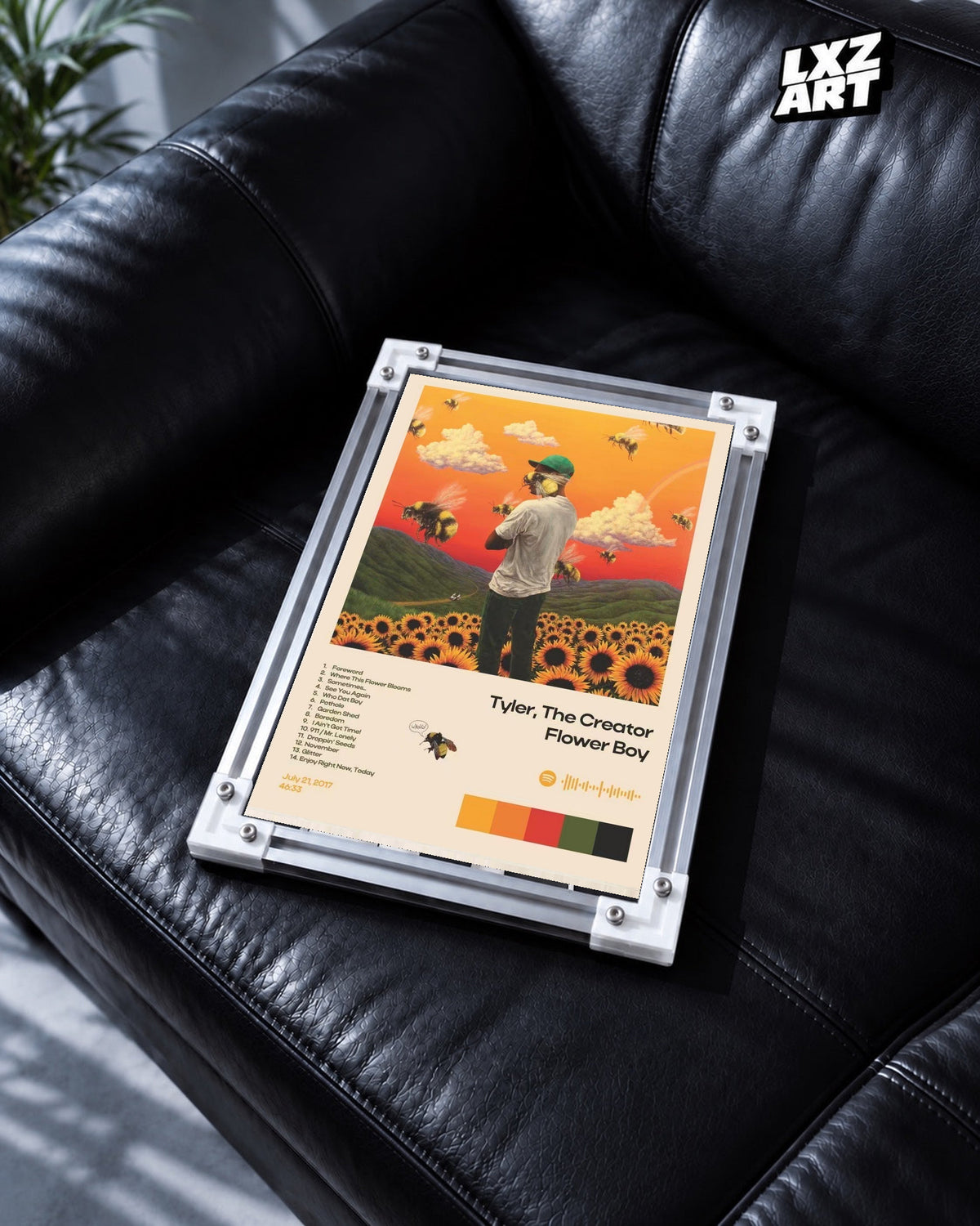 Tyler, The Creator Flower Boy Tracklist Poster in white-corner frame on black leather sofa. Frame shown for display only.