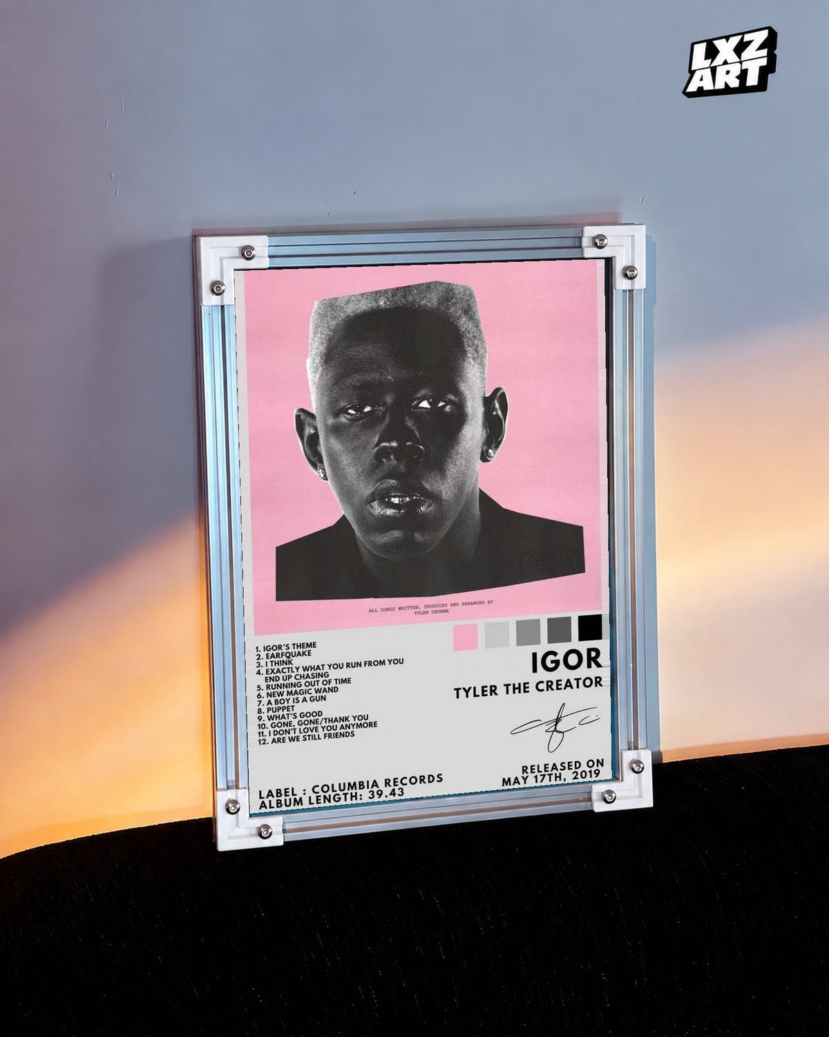 Tyler, The Creator IGOR Tracklist Poster in white-corner frame beside warm-lit wall. Frame shown for display only.