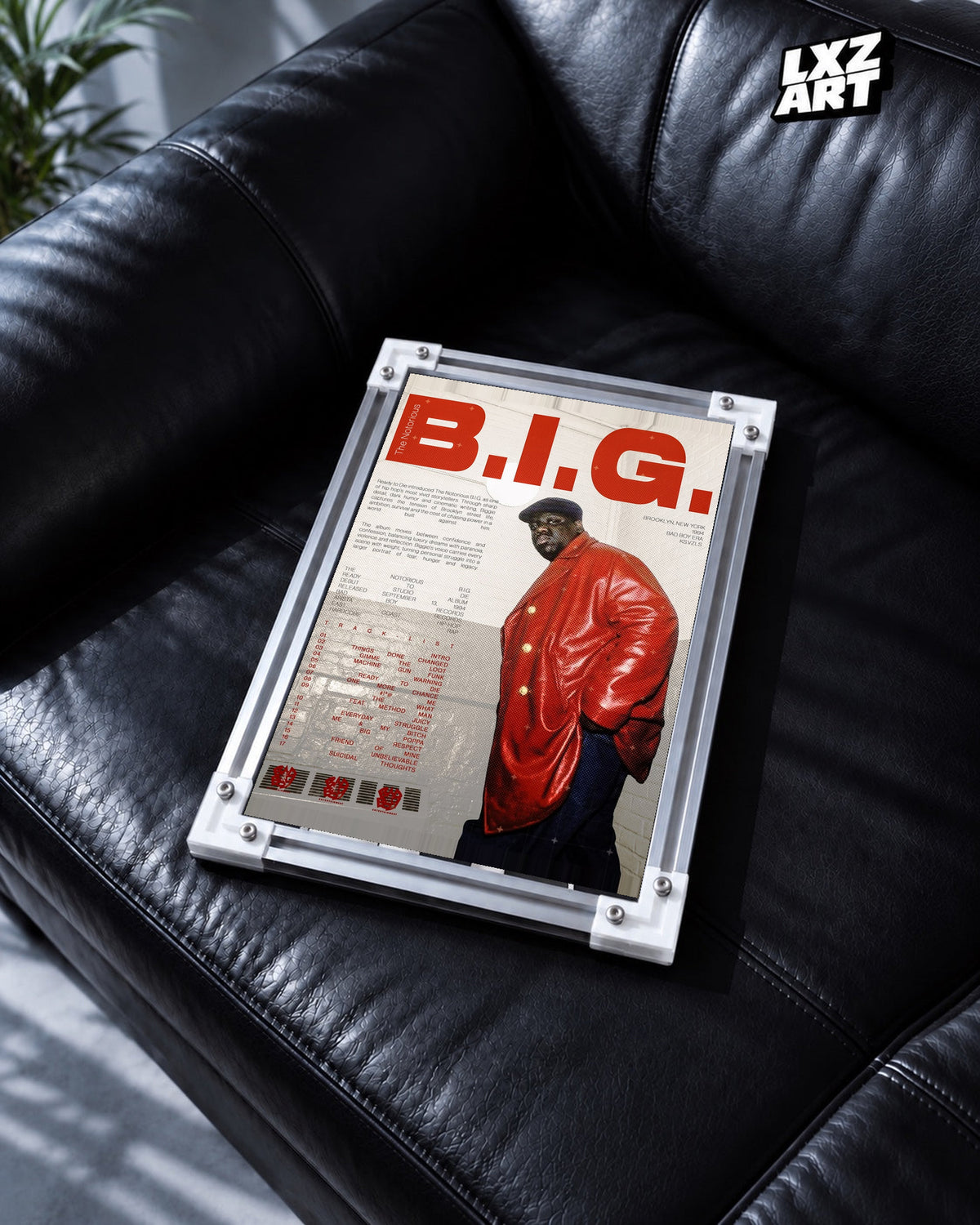 The Notorious B.I.G. Ready to Die Red Jacket Tracklist Poster in white-corner frame on black leather sofa. Frame shown for display only.
