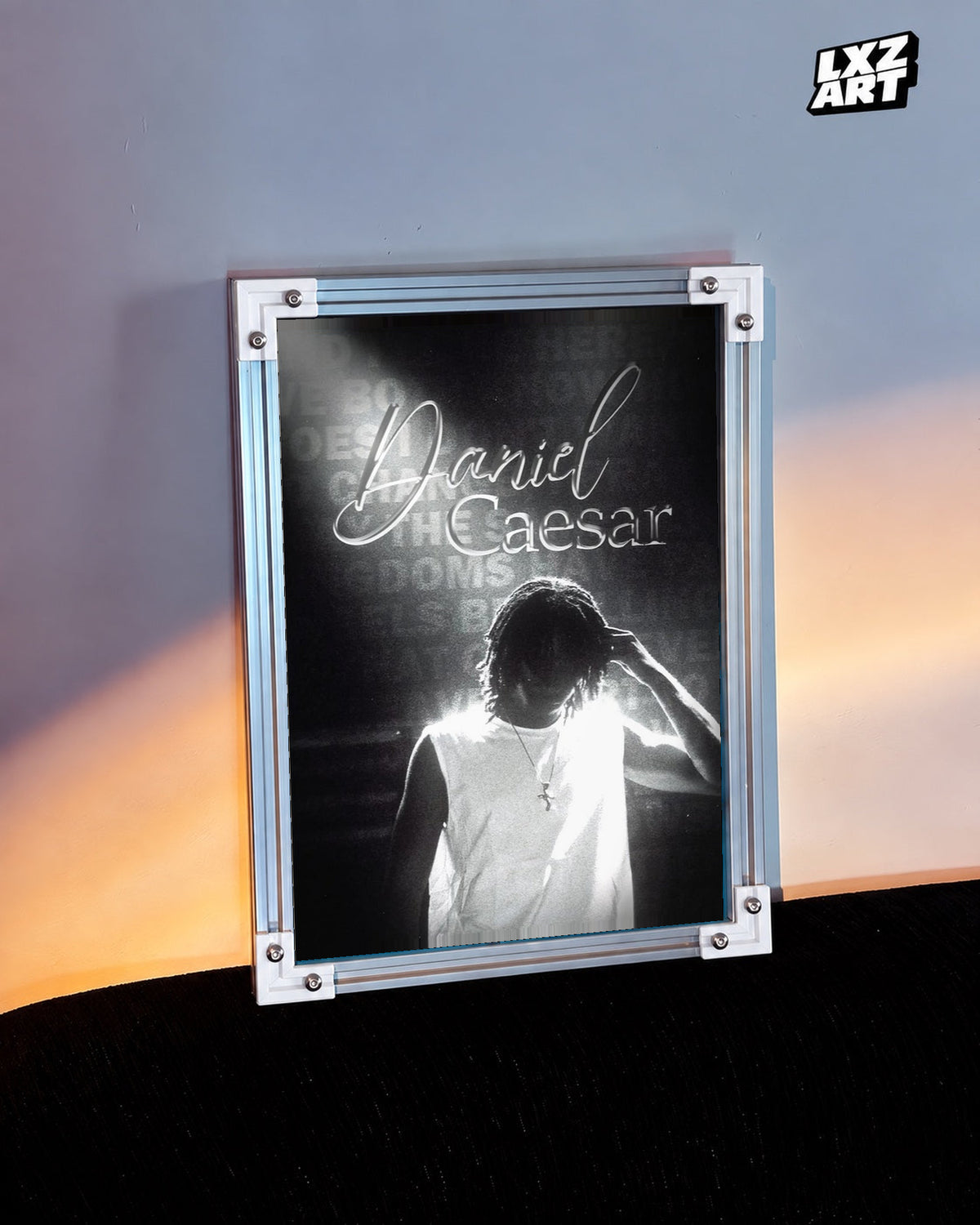 Daniel Caesar Black & White Backlit Portrait Poster in white-corner frame beside warm-lit wall. Frame shown for display only.