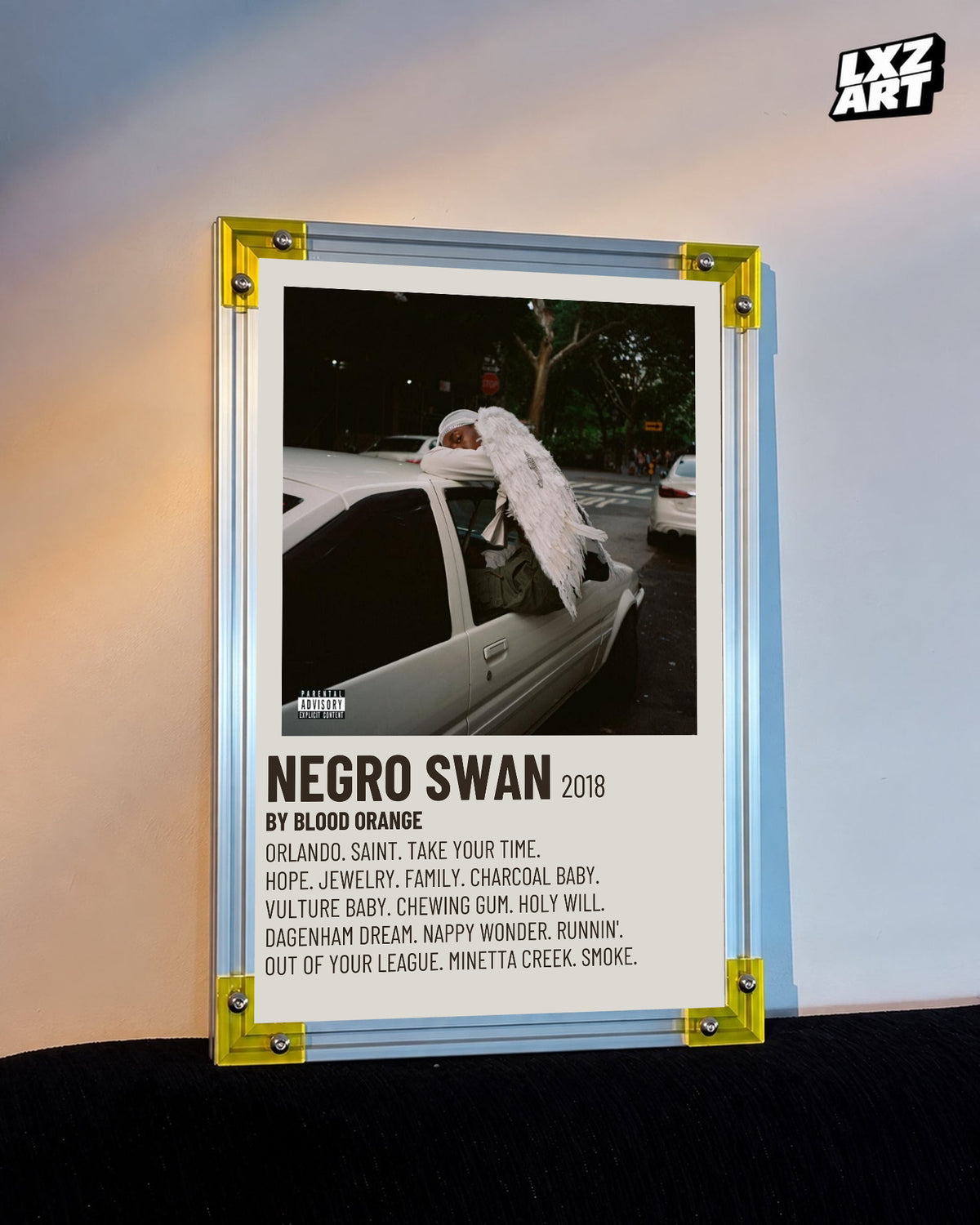 Blood Orange Negro Swan cream tracklist poster displayed against a warm-lit wall in the yellow-corner frame; unframed print, frame not included