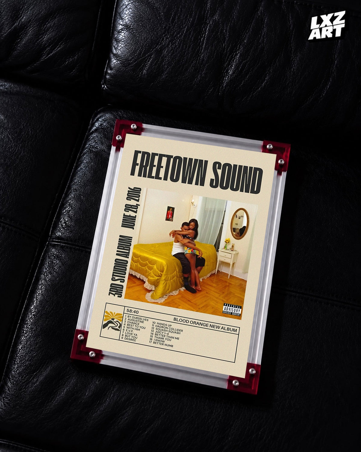 Blood Orange Freetown Sound bold title tracklist poster displayed on a black leather sofa in the red-corner frame; unframed print, frame not included
