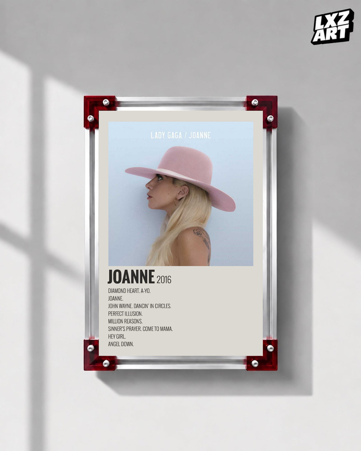 Lady Gaga Joanne tracklist poster displayed on a gray wall in a red corner frame; unframed print, frame not included