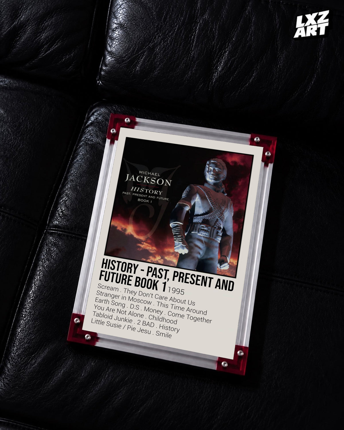 Michael Jackson HIStory Past, Present and Future Book I tracklist poster displayed on a black leather sofa in a red corner frame; unframed print, frame not included