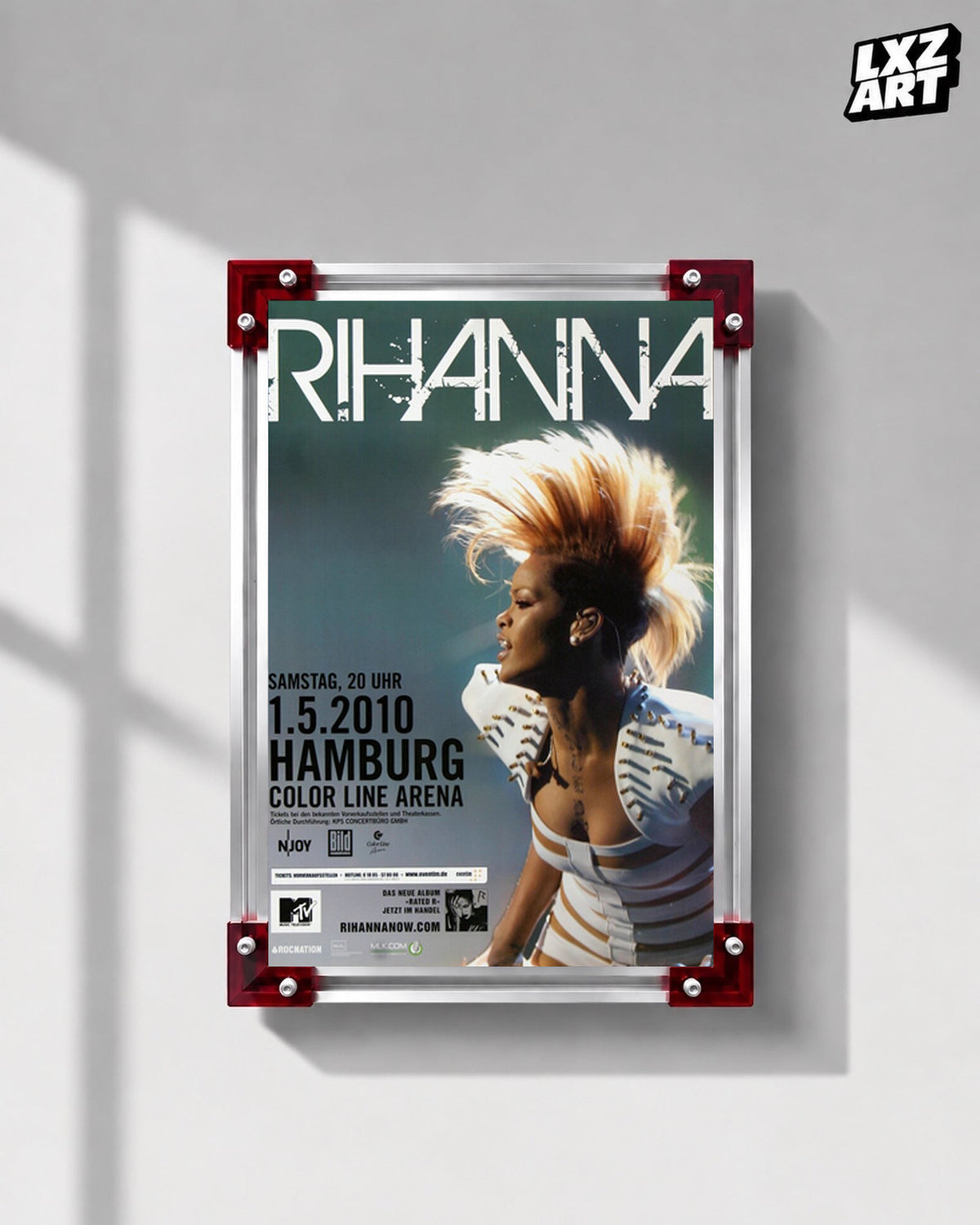 Rihanna Rated R Hamburg 2010 concert poster displayed on a gray wall in a red corner frame; unframed print, frame not included