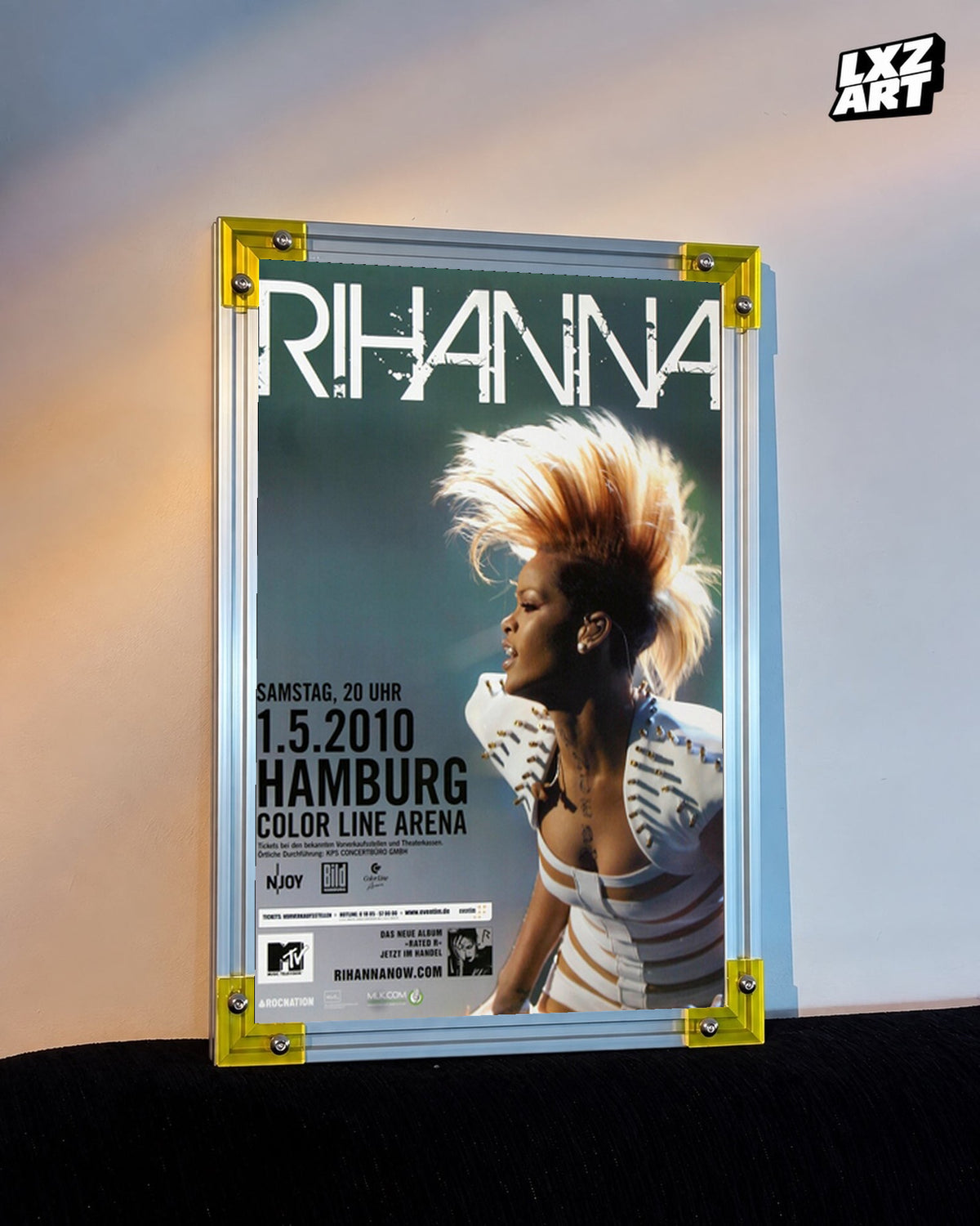Rihanna Rated R Hamburg 2010 concert poster displayed against a warm wall in a yellow corner frame; unframed print, frame not included