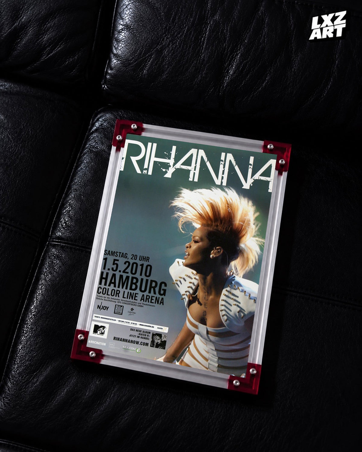 Rihanna Rated R Hamburg 2010 concert poster displayed on a black leather sofa in a red corner frame; unframed print, frame not included