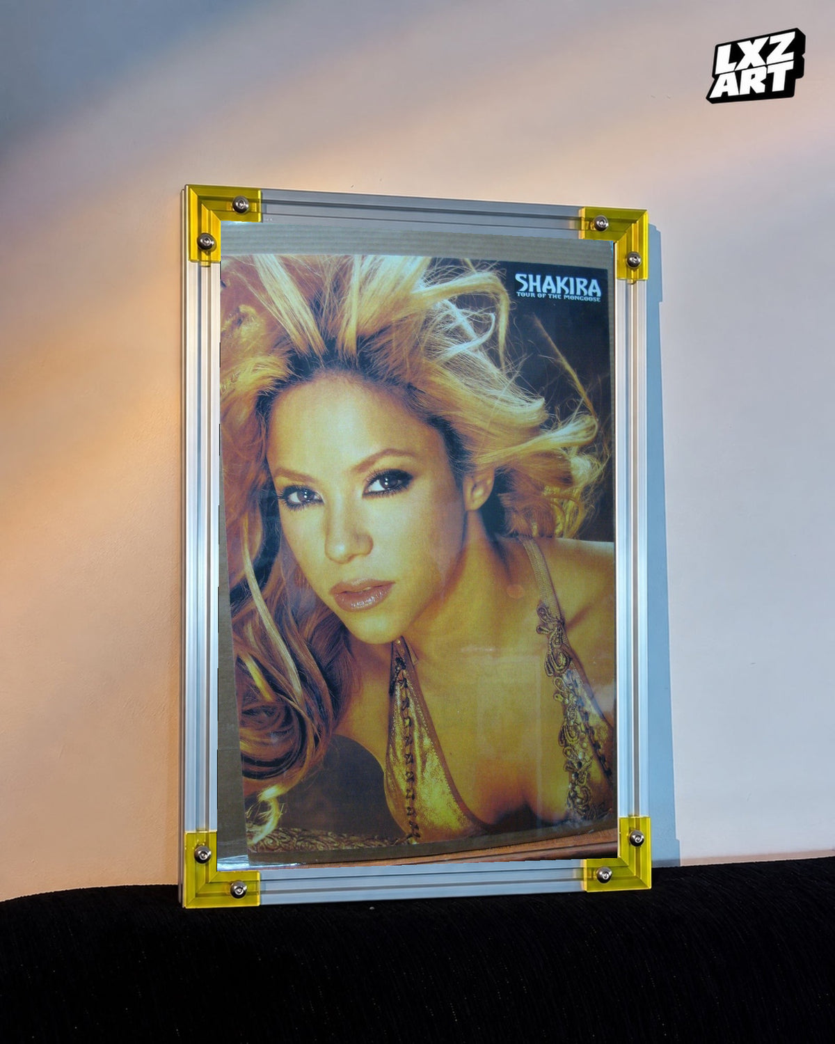 Shakira Tour of the Mongoose concert tour poster displayed against a warm wall in a yellow corner frame; unframed print, frame not included