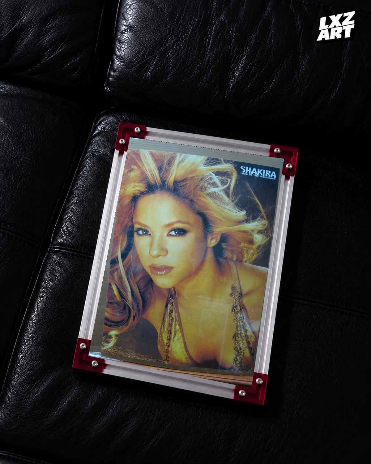 Shakira Tour of the Mongoose concert tour poster displayed on a black leather sofa in a red corner frame; unframed print, frame not included