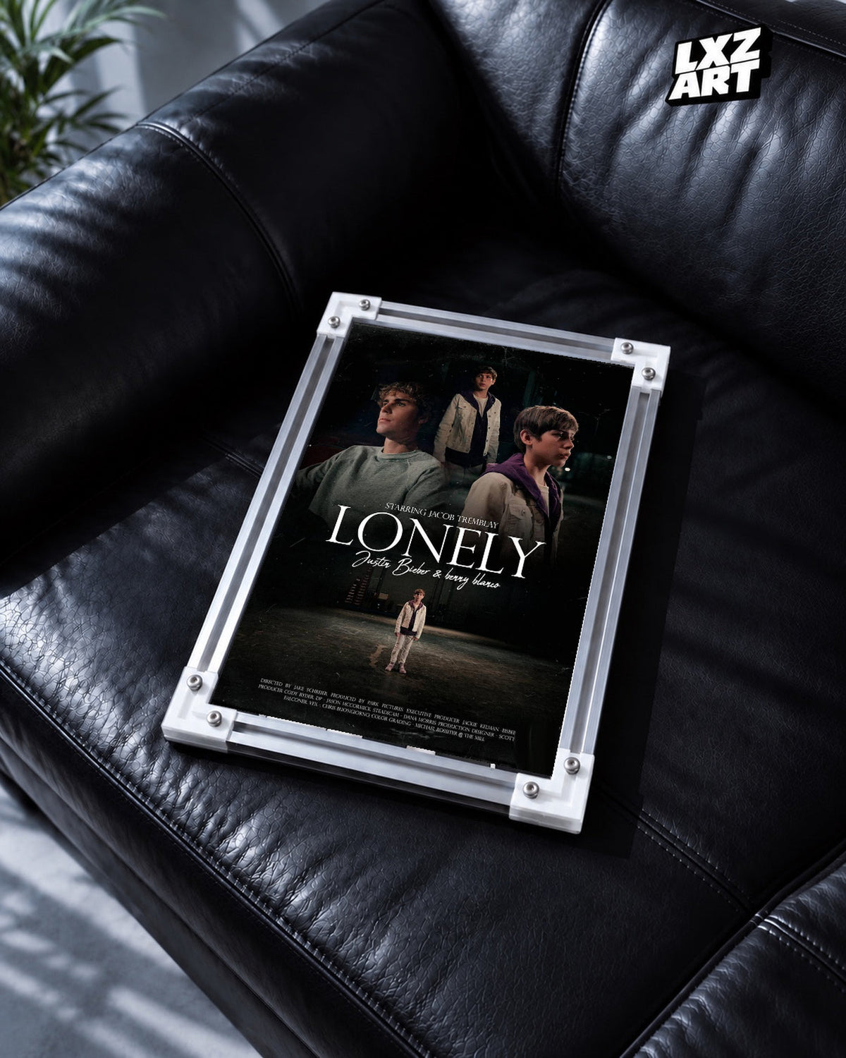 Justin Bieber & benny blanco Lonely Music Video Poster displayed in a white-corner frame on a black leather sofa. Frame for display only.