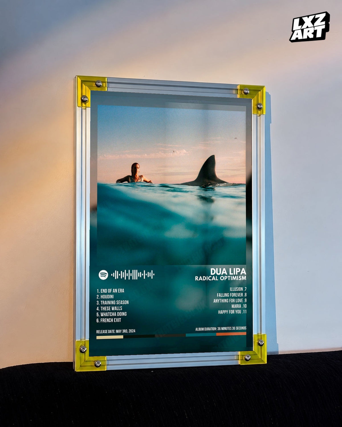 Dua Lipa Radical Optimism Ocean Tracklist Poster displayed on a warm wall in a yellow corner frame; unframed print, frame not included