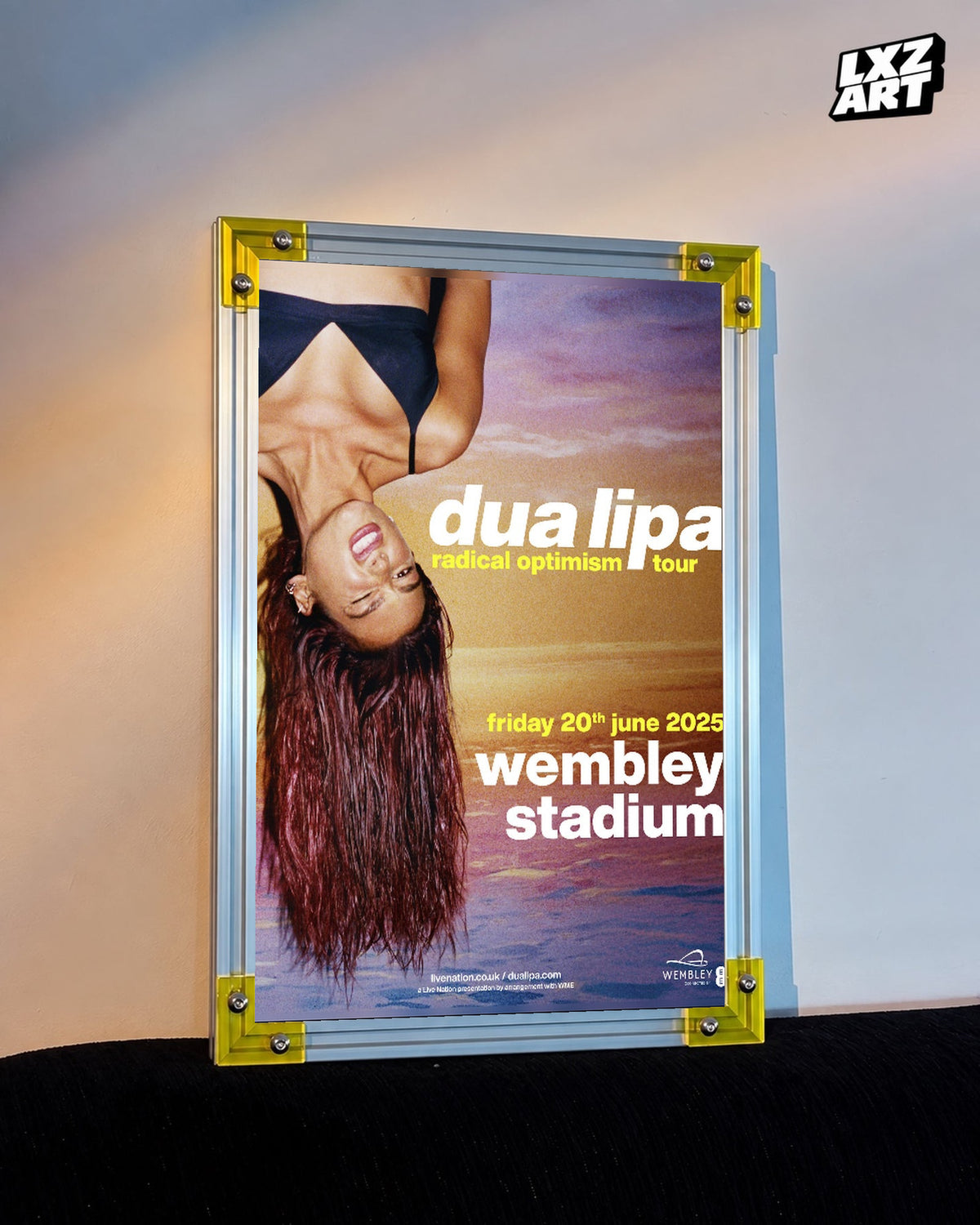 Dua Lipa Radical Optimism Wembley Stadium Tour Poster displayed on a warm wall in a yellow corner frame; unframed print, frame not included