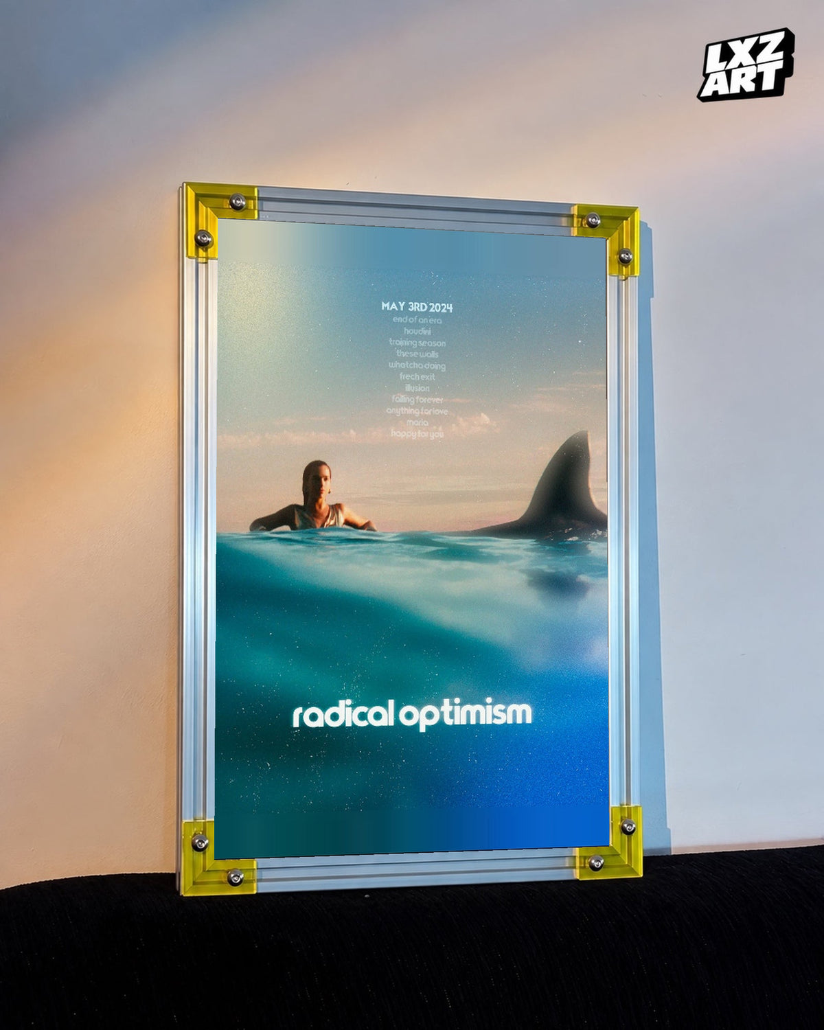 Dua Lipa Radical Optimism Ocean Typography Poster displayed on a warm wall in a yellow corner frame; unframed print, frame not included