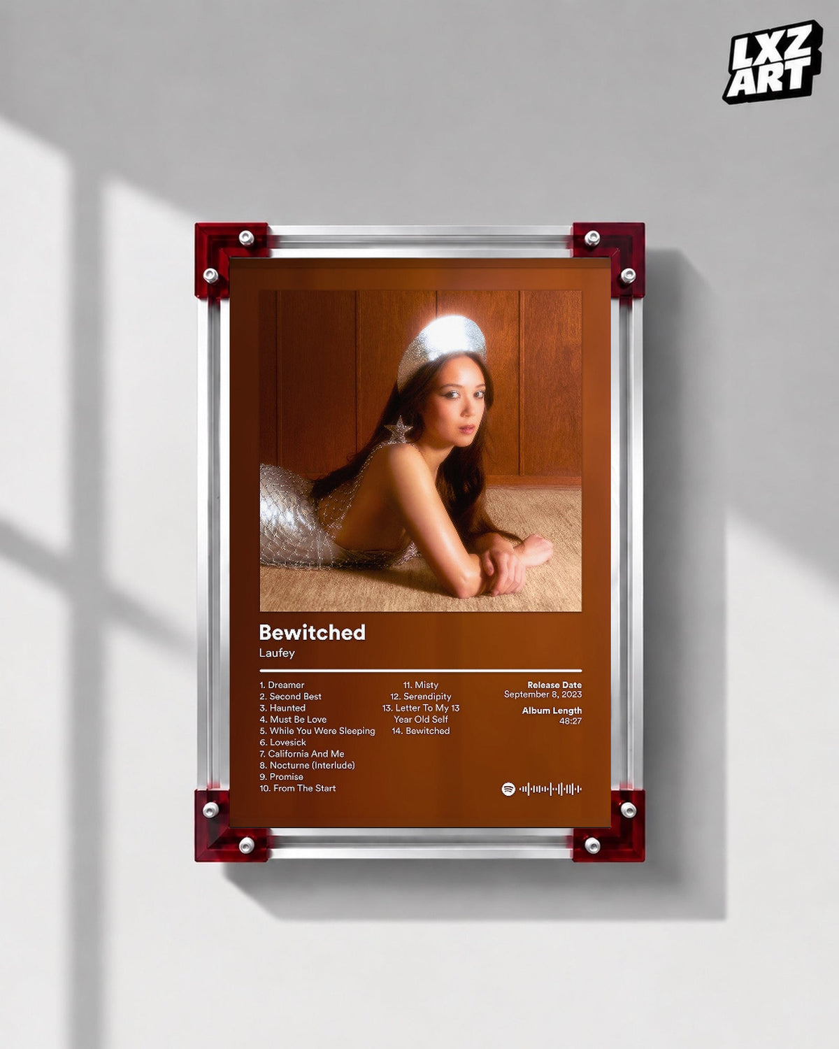 Laufey Bewitched Brown Portrait Tracklist Poster displayed on a gray wall in a red corner frame; unframed print, frame not included