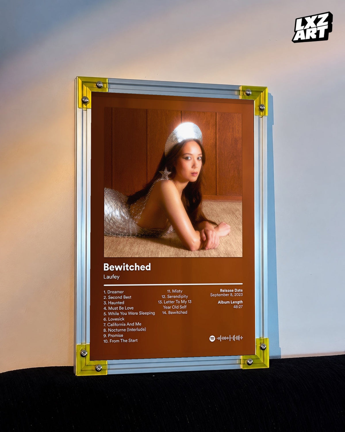 Laufey Bewitched Brown Portrait Tracklist Poster displayed on a warm wall in a yellow corner frame; unframed print, frame not included