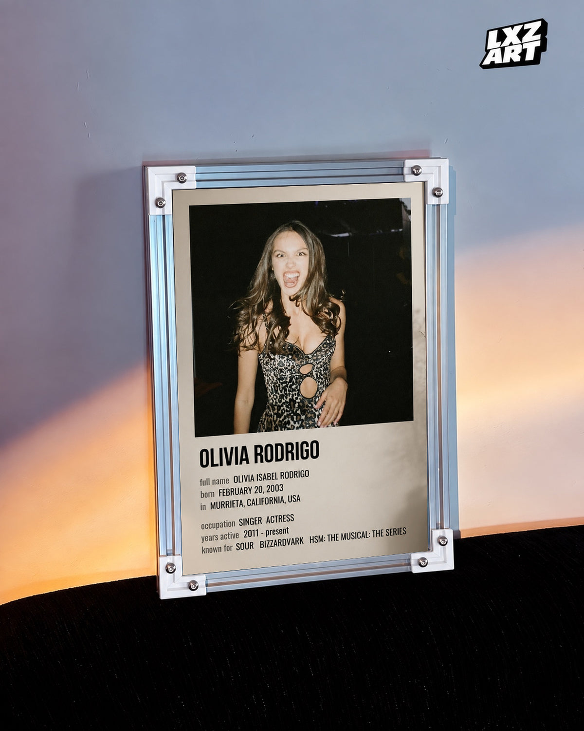 Olivia Rodrigo Biography Portrait Poster — warm light wall; frame for display only